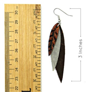 May include: A pair of leather feather earrings in brown, orange, and gray. The earrings are 3 inches long.