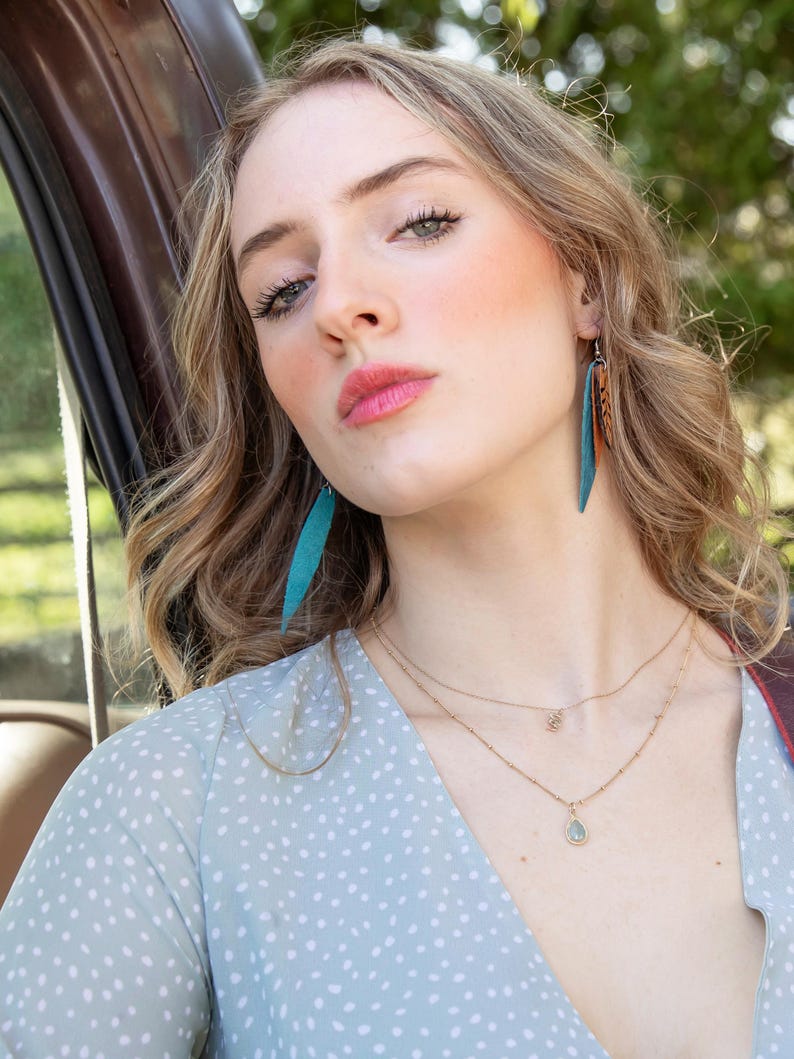 Model wearing the tan and turquoise color feather earrings.