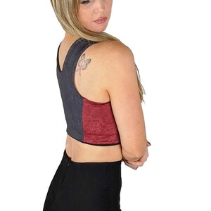 Puede incluir: Una mujer con un top corto de tirantes negro y burdeos con un tatuaje de mariposa en el hombro. Tambi&eacute;n lleva pantalones negros.