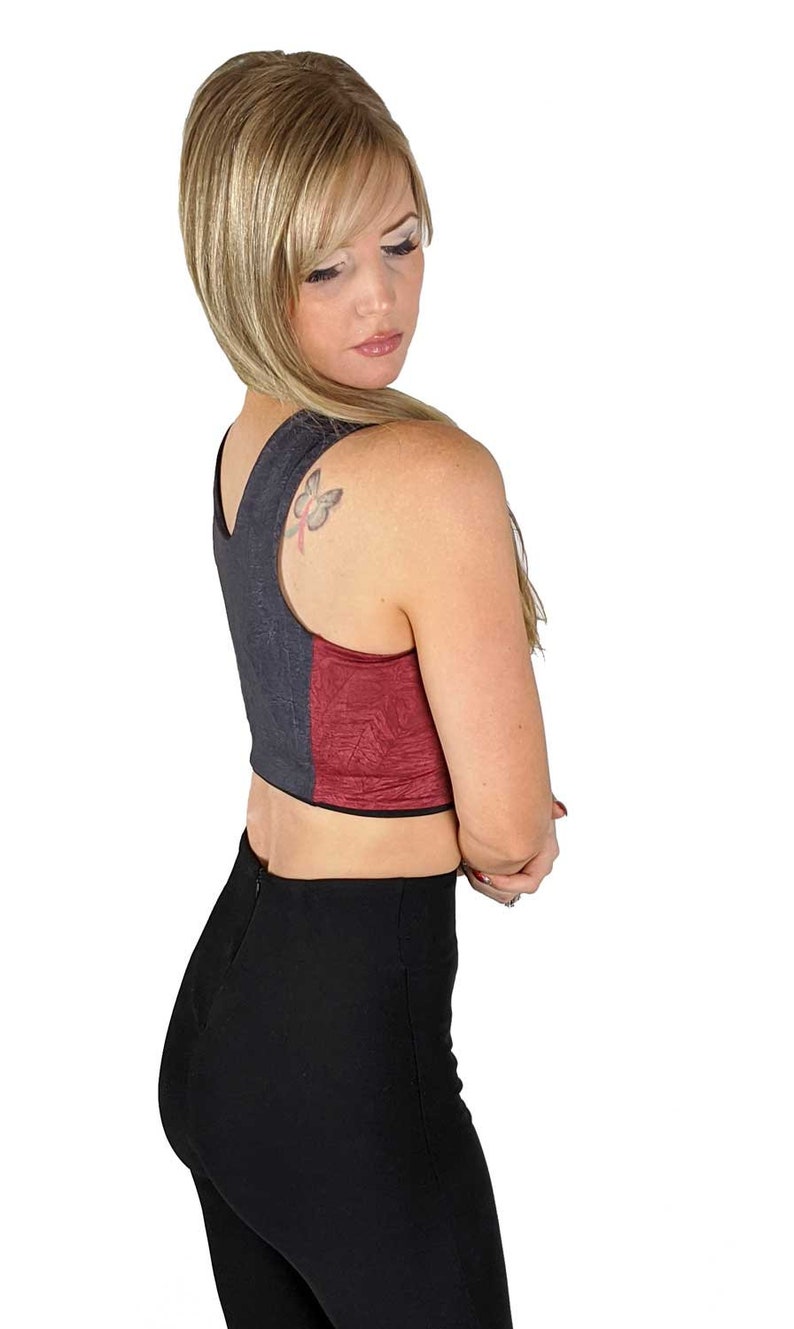 Puede incluir: Una mujer con un top corto de tirantes negro y burdeos con un tatuaje de mariposa en el hombro. Tambi&eacute;n lleva pantalones negros.