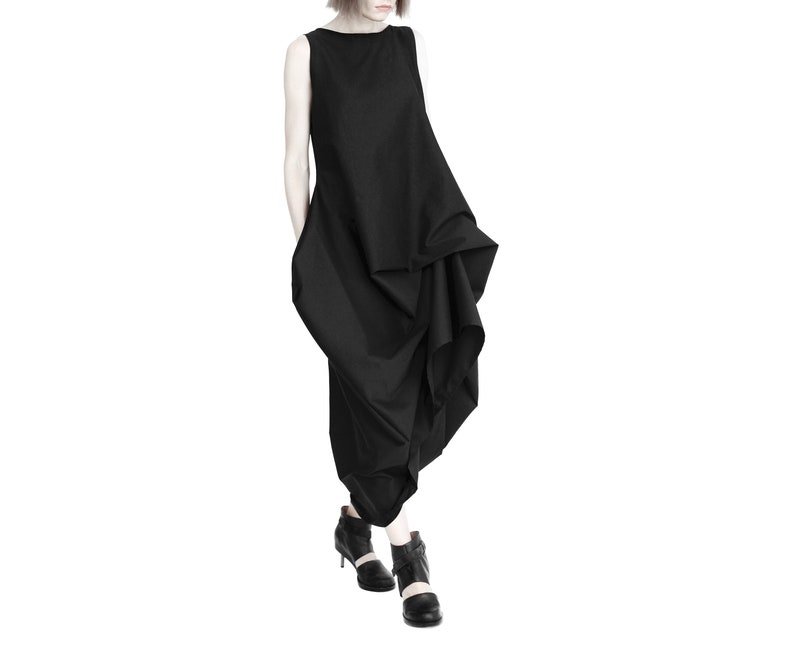 May include: A black sleeveless dress with a flowing, asymmetrical design. The dress is made of a lightweight fabric and has a relaxed fit.