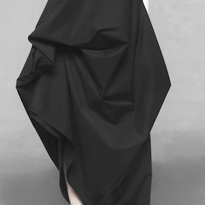 May include: A black, flowing dress with a draped, asymmetrical design. The dress is made of a soft, lightweight fabric and has a relaxed fit.
