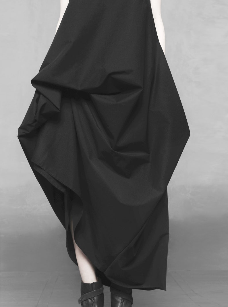 May include: A black, flowing dress with a draped, asymmetrical design. The dress is made of a soft, lightweight fabric and has a relaxed fit.