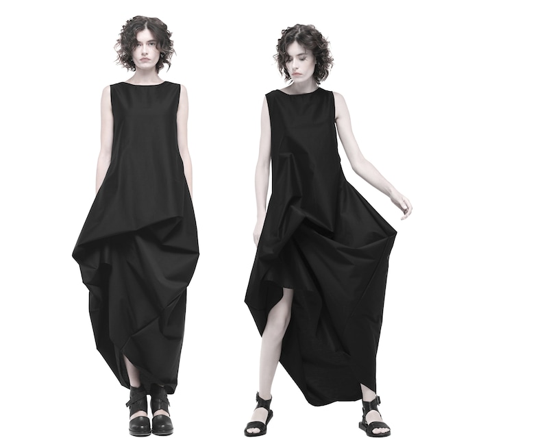 May include: A black sleeveless dress with a flowing, asymmetrical skirt. The dress is made of a lightweight fabric and has a simple, elegant design.