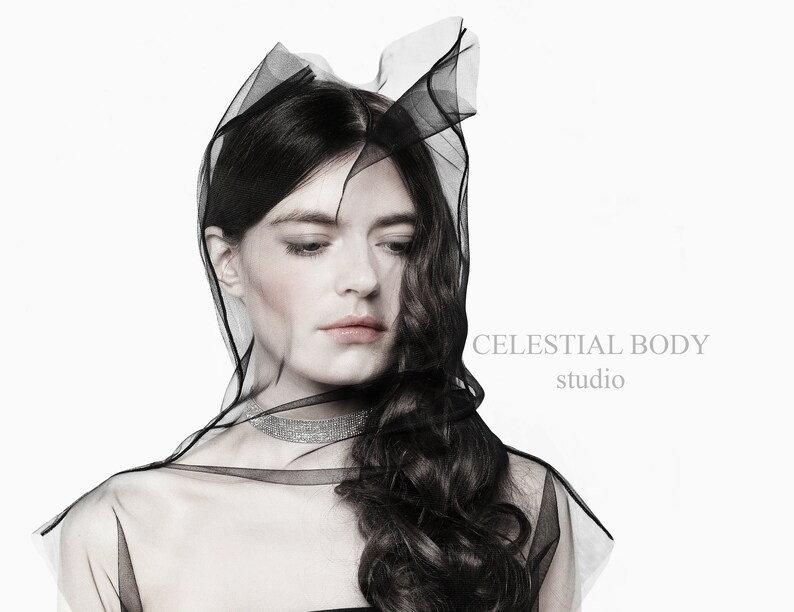 May include: A woman with long dark hair wears a black sheer veil and a silver choker necklace. The text "CELESTIAL BODY studio" is visible in the background.