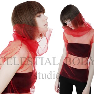 May include: Two women wearing red sheer tops. The tops are layered over a burgundy bandeau top. The women have short brown hair.