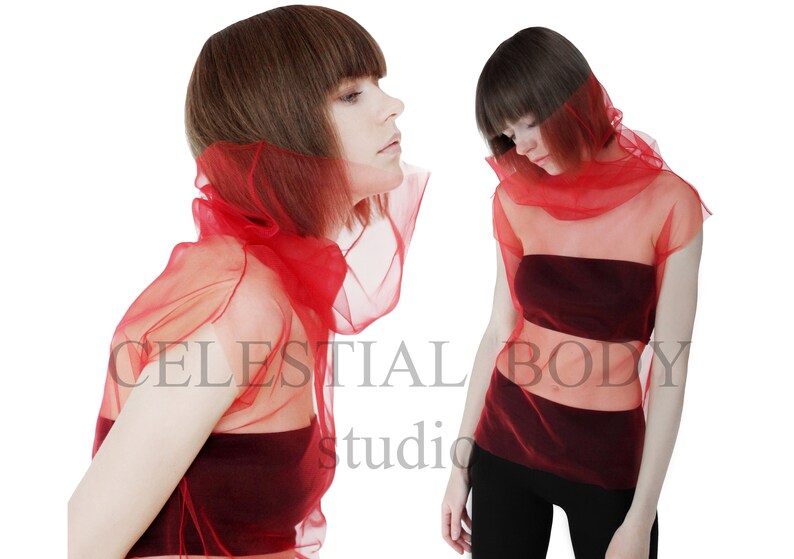 May include: Two women wearing red sheer tops. The tops are layered over a burgundy bandeau top. The women have short brown hair.