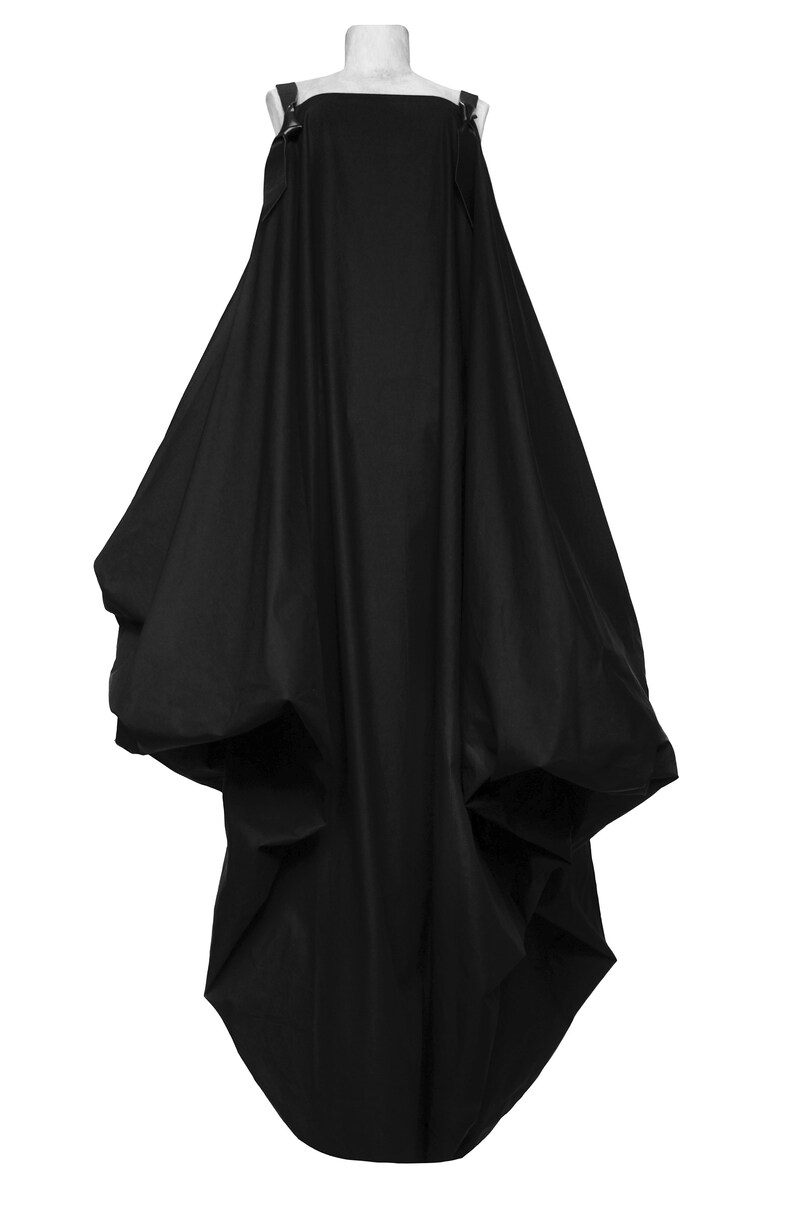 Puede incluir: Un vestido negro, sin tirantes, largo hasta el suelo, con una falda amplia y voluminosa y tirantes ajustables.