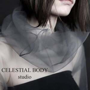 May include: A woman wearing a sheer gray top with a black tank top underneath. The text "CELESTIAL BODY studio" is visible on the image.