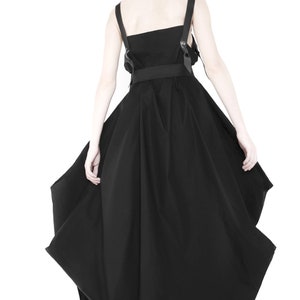 Puede incluir: Un vestido negro con un dise&ntilde;o asim&eacute;trico &uacute;nico. El vestido presenta un corpi&ntilde;o ajustado con una falda amplia y fluida que cae de forma espectacular.