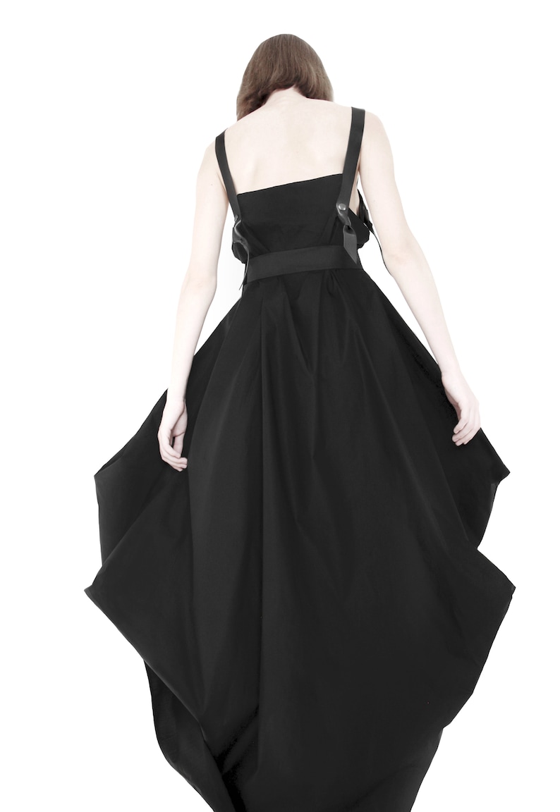 Puede incluir: Un vestido negro con un dise&ntilde;o asim&eacute;trico &uacute;nico. El vestido presenta un corpi&ntilde;o ajustado con una falda amplia y fluida que cae de forma espectacular.