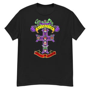 Puede incluir: Camiseta negra con un diseño de cruz morada y blanca con caras de robot y el texto "DEVASTATOR" en amarillo. Debajo de la cruz está el texto "APPETITE FOR CONSTRUCTION" en rojo.