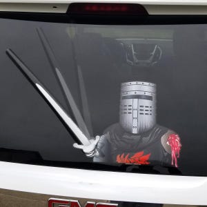 May include: A rear window decal featuring a knight in silver armor holding a sword. The knight has a silver helmet and a red and black emblem on the chest. The wiper blade is designed to look like the knight's sword.