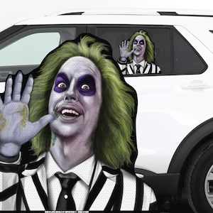 May include: A large car window decal featuring a character from the movie Beetlejuice. The character is wearing a black and white striped suit and has green hair and a wide smile. The decal is printed on a clear background and is designed to be placed on the inside of a car window.