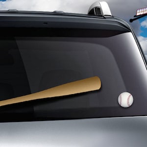 May include: A brown baseball bat and a white baseball with red stitching are on the back window of a silver car. The car is parked in a parking lot.