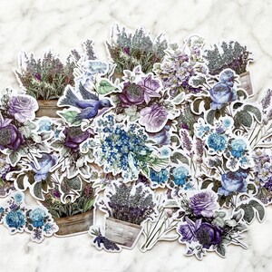 K&ouml;nnte beinhalten: Eine Sammlung von Lavendel- und Blumenstickern mit einem blauen Vogel, perfekt zum Scrapbooking, Journaling oder um deinen Bastelarbeiten einen Hauch von Verspieltheit zu verleihen.