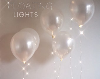 May include: White balloons with string lights inside, floating against a white background. The text "FLOATING LIGHTS" is at the top of the image.