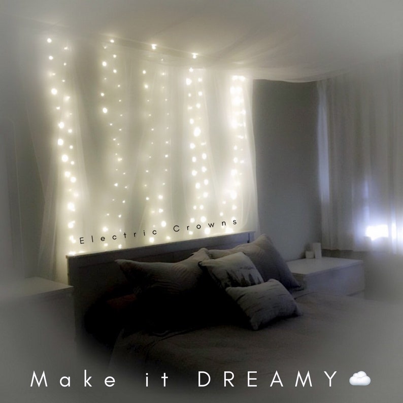 Peut inclure: Une chambre &agrave; coucher avec un lit &agrave; baldaquin blanc drap&eacute; de tissu blanc transparent et de lumi&egrave;res f&eacute;&eacute;riques blanches. Le texte "Electric Crowns" est visible sur la t&ecirc;te de lit. La l&eacute;gende "Make it DREAMY" est en bas de l'image.