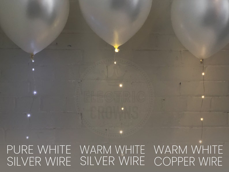 May include: Three white balloons with string lights. The text at the bottom reads "Pure White Silver Wire", "Warm White Silver Wire", and "Warm White Copper Wire". The lights are small and round.