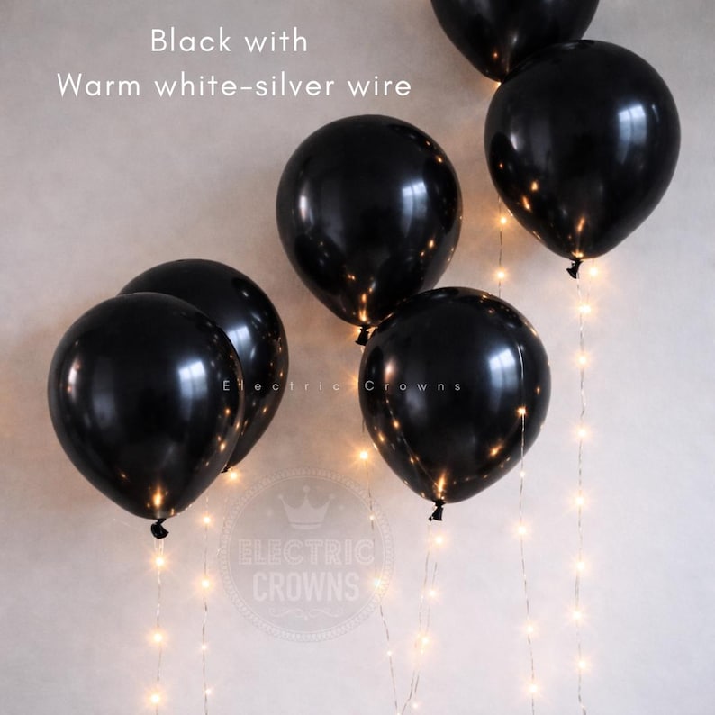 May include: Black balloons with warm white-silver wire lights. The balloons are round and shiny, with the text "Black with Warm white-silver wire" at the top. The logo "Electric Crowns" is at the bottom.