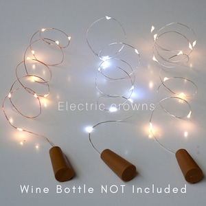 May include: Three sets of copper wire fairy lights with cork stoppers. The lights are in warm white, cool white, and warm white. The text "Electric crowns" is printed on the image. The text "Wine Bottle NOT Included" is printed on the image.