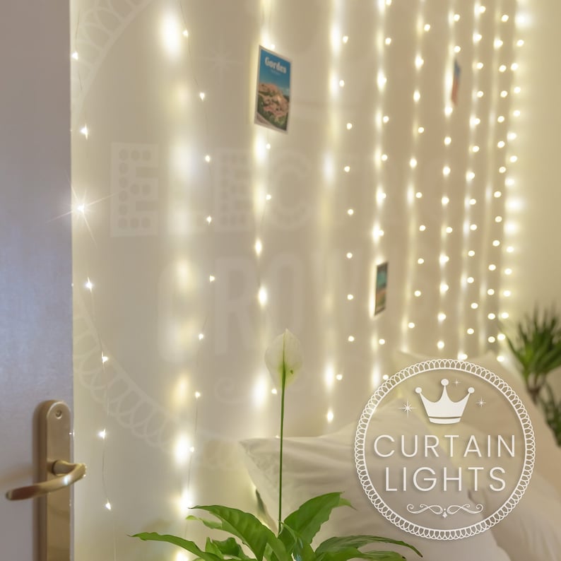 May include: White fairy lights strung across a wall, creating a curtain effect. The lights are warm white and create a soft glow. The text "CURTAIN LIGHTS" is visible in the image.