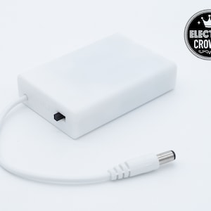 May include: A white power adapter with a black on/off switch and a white power cord with a black plug. The adapter has the text "Electric Crowns" with a crown icon.