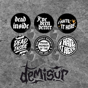 May include: A collection of black circular buttons with white text. The buttons feature phrases like "dead inside," "I've been better," and "I hate it here." One button reads "Sad Skull Society, Proud Member of the Est. 2021."