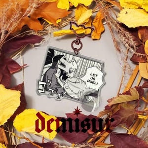 May include: A black and white anime-style illustration of two characters in a fight scene. The characters are wearing armor and one is holding a sword. The text "Let us duel!" is in a speech bubble. The image is printed on a clear acrylic keychain.
