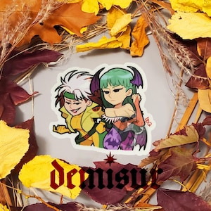 May include: A sticker featuring a cartoon illustration of two characters. The character on the left is a white-haired man with a yellow and green costume. The character on the right is a woman with green hair and a purple and black costume. The sticker has a white background and the text "Demisu" is printed below the characters.
