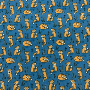 Può includere: Motivo ripetuto di volpi arancioni in varie pose su sfondo blu. Le volpi sono stilizzate con contorni neri e sono intervallate da piccole illustrazioni di piante verde scuro. Il design generale ha un tema stravagante ispirato alla natura.