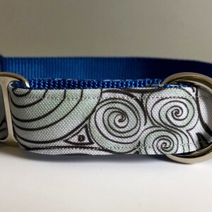 May include: A blue and white dog collar with a silver buckle and a swirling pattern.
