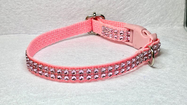 May include: Pink dog collar with a double row of clear pink rhinestones.