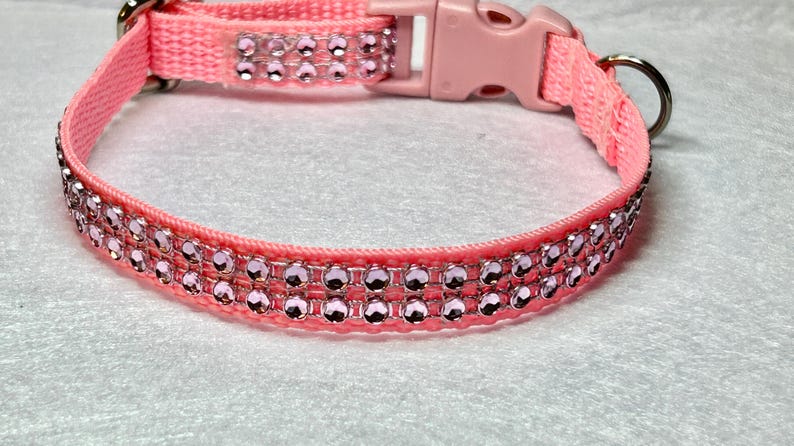 May include: A pink nylon dog collar with a plastic buckle and two rows of pink rhinestones.
