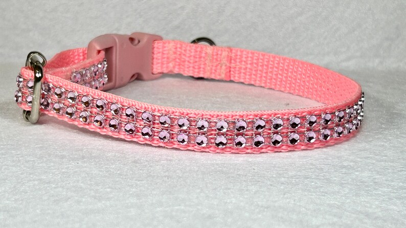 May include: A pink nylon dog collar with a silver buckle and two rows of pink rhinestones.