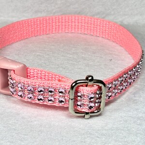 May include: A pink nylon dog collar with a silver buckle and two rows of clear pink rhinestones.