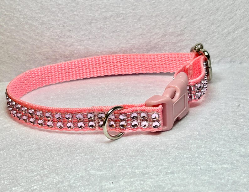 May include: Pink dog collar with a silver buckle and two rows of pink rhinestones.