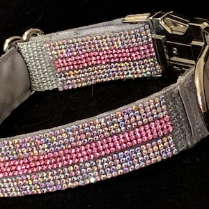 May include: A grey dog collar with a pink and iridescent rhinestone design. The collar has a silver buckle and D-ring.
