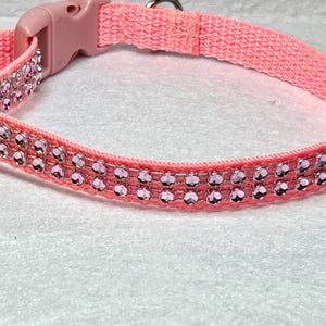 May include: A pink dog collar with two rows of light pink rhinestones.