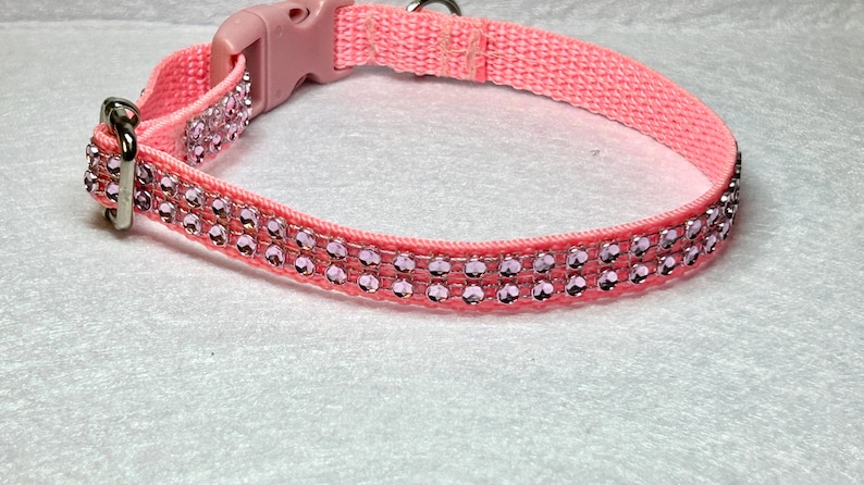 May include: A pink dog collar with two rows of light pink rhinestones.
