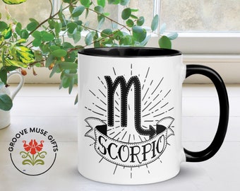 May include: White ceramic mug with a black rim and handle. The mug features a black and white illustration of the Scorpio zodiac sign with the word "Scorpio" on a banner.