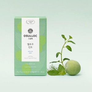 May include: A green box of OSULLOC Mellow Mint herb tea with the text "CAFFEINE FREE". The box has a light green background with green circular designs. A sprig of mint and a green sphere are next to the box.