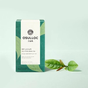 May include: A green and white box of Osulloc Jeju Pure Green Tea. The box features text in Korean and English, along with a leaf design. A sprig of green tea leaves rests on the right side of the box. The box contains 40 g of tea.