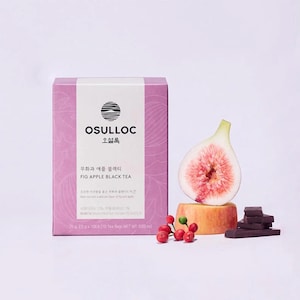 May include: A box of Osulloc Fig Apple Black Tea with a fig half, a piece of fruit, and dark chocolate. The box is light purple with white text and a logo. The tea box has the words "FIG APPLE BLACK TEA" on it.