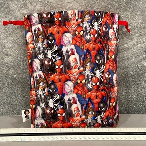 May include: Red drawstring bag with a pattern of various Spider-Man characters, including Spider-Man, Spider-Gwen, and Miles Morales.
