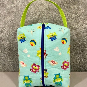 May include: A light blue zippered pouch with a green handle. The pouch is decorated with a repeating pattern of alien characters from the Toy Story franchise.