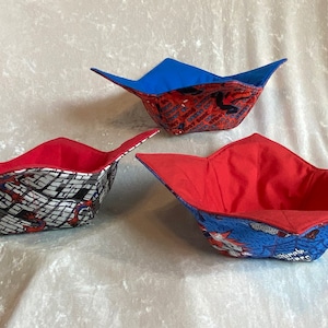 May include: Three fabric bowls, one blue with red and white pattern, one red with black and white pattern, and one red with blue and white pattern.