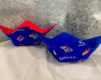 May include: Two blue and red fabric bowl cozies with a Kansas Jayhawks logo and the words "Kansas" and "KU".