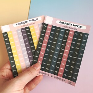 Op de afbeelding: Twee vellen met kleurrijke budgetstickers met de tekst "Paid Budget Stickers" en "Illustrated by Julia Freeman". De stickers zijn in rijen van cirkels gerangschikt, met in elke cirkel het woord "Paid".