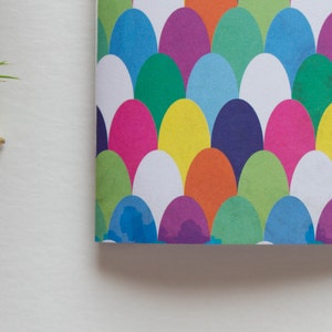 Puede incluir: Una cubierta de cuaderno colorida con un patr&oacute;n de c&iacute;rculos superpuestos en tonos de azul, verde, morado, amarillo, naranja, rosa y blanco.